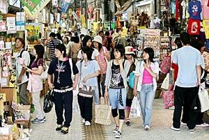 Young tourists stroll on the main shopping street in Naha, Okinawa Prefecture, Japan.