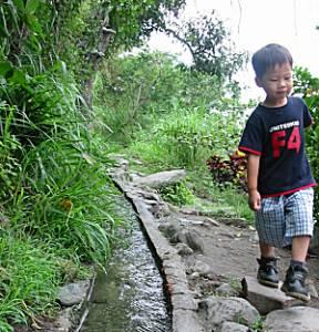 A young boy demonstrates the miracle of "Water Running Up"