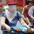 A masked woman wearing long gloves rides a motorcycle in Hanoi. Beauty in the minds of most Vietnamese women means white skin-a symbol of feminity, pureness, sophistication and high social class.