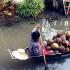 A vendor carries coconuts on the way to a nearby floating market.