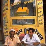 Two men reading newspapers by a stamp kiosk. Nepalganj, Nepal.