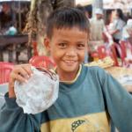A young boy helps his mother sell souvenirs at an outdoor stand near Angkor Wat