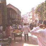 Bombay, India. The harsh Bombay sun blazes on this Dongri sidestreet, where vendors sell bananas and a minaret is under construction.