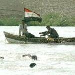 Iraqi coach of the Olympic swimming team, Said Jaafar (R), gives instruction to his team members from a row boat as they practice in the Tigris river in Baghdad