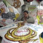 A shopkeeper gives the final touches to a kite decorated with a dragon and slogans to symbolise the Indian occupation in disputed Kashmir, on the eve of the annual kite-flying festival, locally known as 'Basant', in the eastern city of Lahore, 07 February 2003. This is first time that kite manufacturers have printed slogans about the current affairs of the world during the Basant festival. Basant is celebrated at the onset of each spring with an orgy of kite-flying, roof top soirees, garden parties and equestrian events.