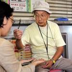 Seventy-eight-year-old fortune-teller Terutsugu Eguma attends to a customer on the street of Ginza shopping district of Tokyo.