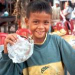 A boy helps his mother sell souvenirs near the front entrance to Angkor Wat.