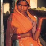 The climate of the desert state of Rajasthan, India is hot and dry and the main form of transportation is by camel. I was traveling through on a camel safari when we stopped, late in the afternoon, at a small village. A young woman with a golden bowl balanced on her head came out of an old house near where the camels had been tied. The light was warm and I motioned with my camera. She took the bowl off her head and let me take one frane before she disappeared back into her house. - Kraig Lieb, 1989.