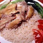 A plate of chicken rice topped with chicken wings and vegetables. Brought to Singapore by the people of Hainan, an island off the southern-coast of China, this is a national dish loved by Singaporeans.