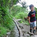 A young boy demonstrates the miracle of "Water Running Up"