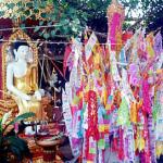 You bump into the trunk of a giant, sinewy tree with spade-like leaves: "a Bo, or Bodhi tree. Often gated and containing a sitting Buddha and his disciples, the Bodhi tree is sacred to Buddhists, being the tree under which the Buddha became enlightened. Some trees are purported to have grown from clippings of the original tree in Bodh Gaya, India." Adjacent the Bo tree is a structure suggesting the aftermath of a construction-paper factory explosion, "a dtoong. Every Thai New Year, cartloads of sand are brought into the temple, formed into a pagoda shape, and stuck through with these colorful strips of crepe, ornately cut and inscribed. Temple-goers believe that through a year's traffic, the temple has lost this much sand; this merit-making act is their way of returning it."